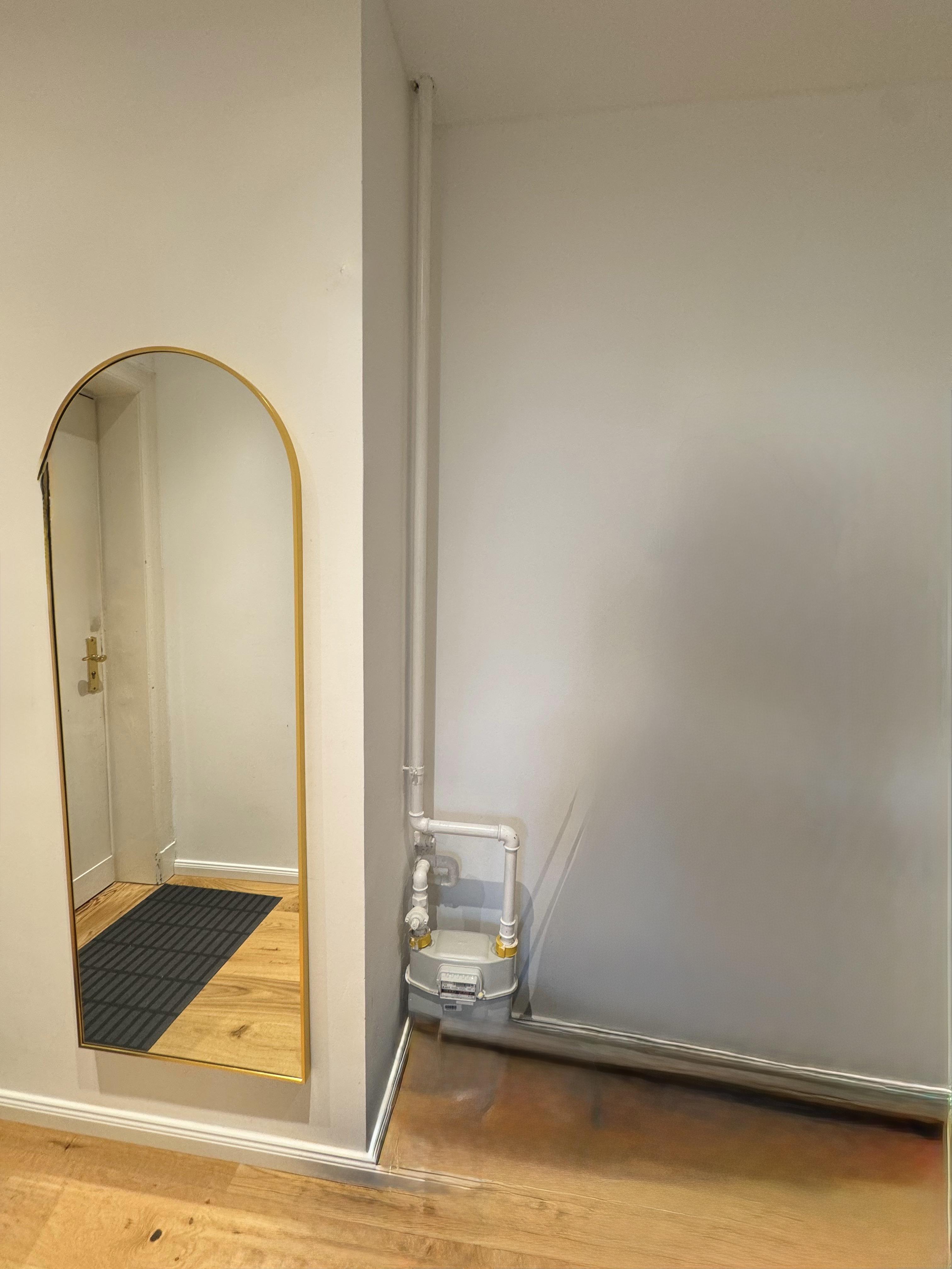 Before photo of exposed gas pipes in apartment entrance